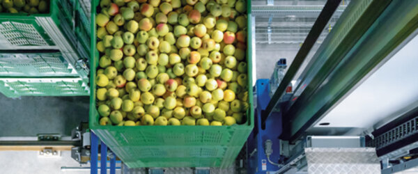 Regalbediengeräte mit einer Kiste voller Äpfel auf dem Hubschlitten Regalbediengeräte mit einer Kiste voller Äpfel auf dem Hubschlitten