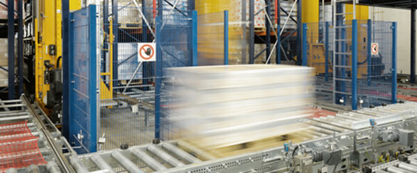 Eine bepackte Palette wurde gerade aus dem Hochregallager ausgelagert und fährt auf der Fördertechnik zur Auslagerungsstelle Eine bepackte Palette wurde gerade aus dem Hochregallager ausgelagert und fährt auf der Fördertechnik zur Auslagerungsstelle