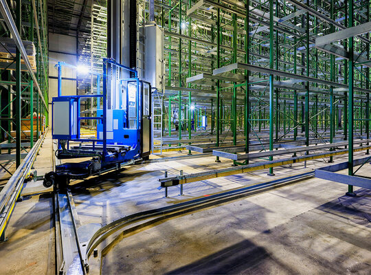 Regalbediengeräte auf Schienen in einer große Lagerhalle  Regalbediengeräte auf Schienen in einer große Lagerhalle